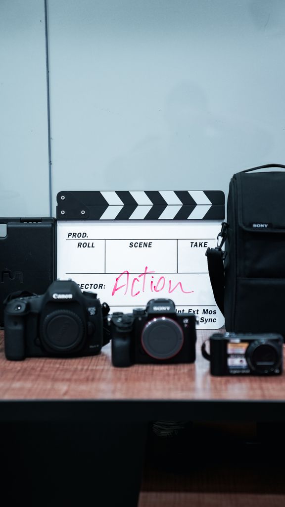Clapperboard and cameras arranged on a desk, ideal for film production themes.